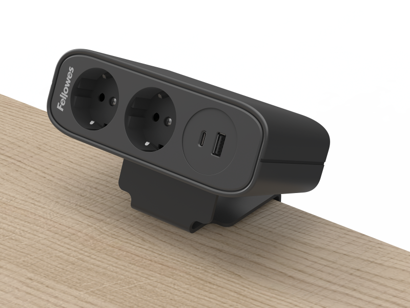 Zwarte stroomunit bevestigd op een bureaublad, zichtbaar zijn twee stopcontacten en een USB-A/C poort